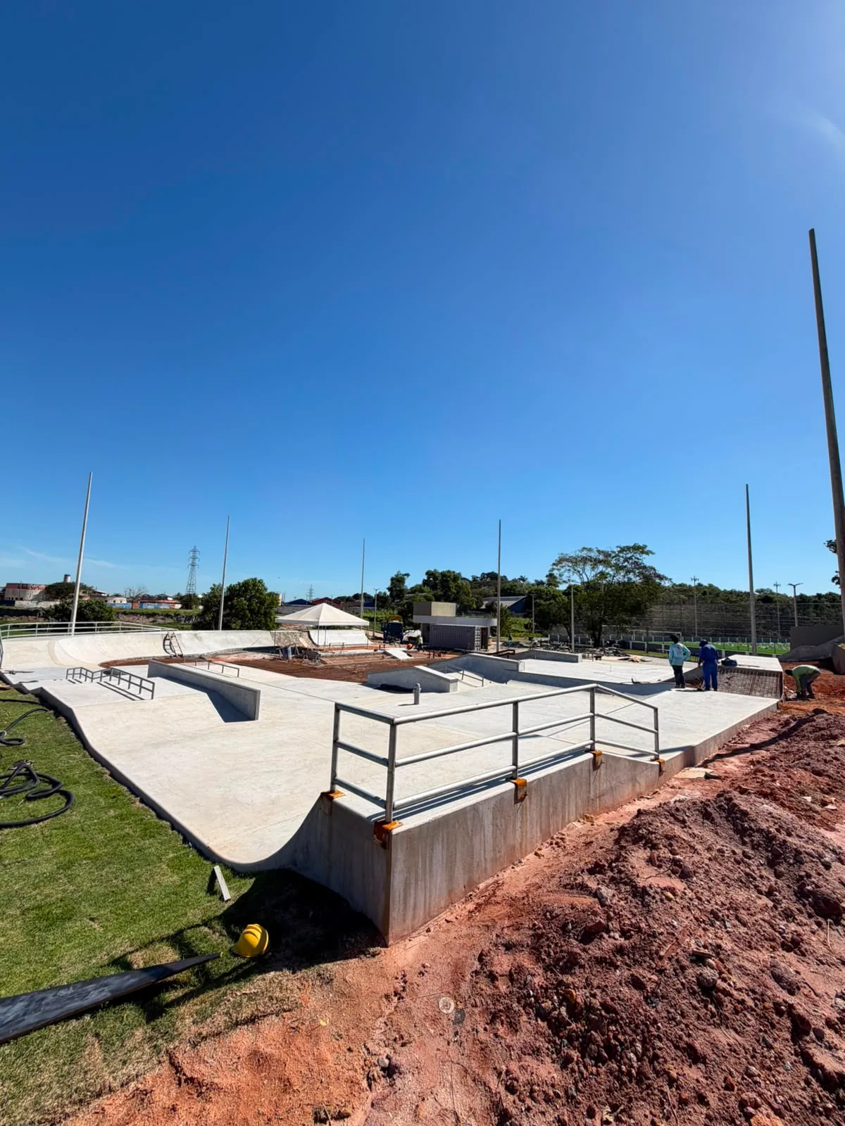 Vista geral de um skatepark em fase final de construção, com obstáculos e corrimãos de concreto